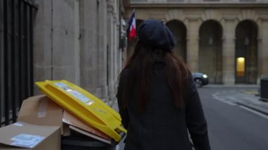 Bere takmış şık bir kadın Paris, Fransa 'da bir sokakta geri dönüşüm kutuları ve karton kutuların yanından geçiyor ve şehir hayatını sergiliyor.. 