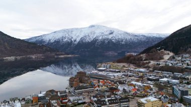 Norveç 'in Sogndal kentinin göz kamaştırıcı hava manzarası karlı bir dağ ve renkli bir kasabayı yansıtan sakin bir fiyort içeriyor..