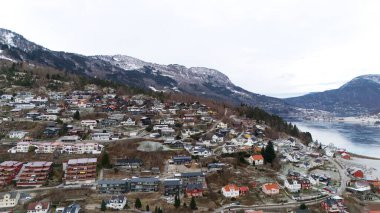 Norveç 'in Sogndal kentinin hava manzarası, büyüleyici yamaç evleri, sakin bir fiyort ve karla kaplı dağ manzaraları.. 