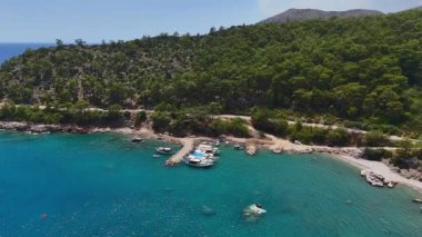 Türkiye 'nin Antalya kentindeki nefes kesen turkuaz bir körfeze yanaşan teknelerin hava manzarası sakin kıyı güzelliğiyle çevrili..