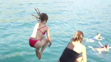 Antalya, Türkiye, 08.20.2024 Bir grup genç heyecanlı bir şekilde yattan açık mavi suya atlıyor, yaz eğlencesi ve özgürlüğünün tadını çıkarıyor. 