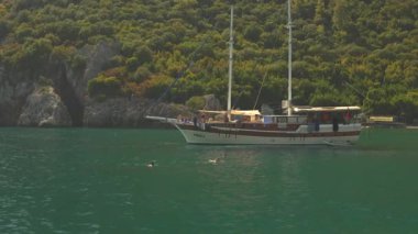 Bir turist yatı, aydınlık ve güneşli bir gökyüzünün altında sakin bir yolculuk deneyimi sunarak engin açık denizde yelken açar. Antalya, Türkiye, 08.20.2024 
