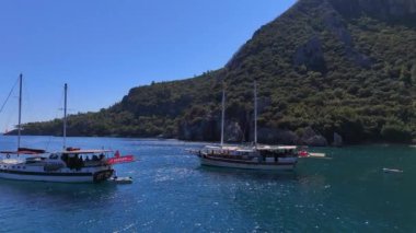 Bir turist yatı, aydınlık ve güneşli bir gökyüzünün altında sakin bir yolculuk deneyimi sunarak engin açık denizde yelken açar. Antalya, Türkiye, 08.20.2024 