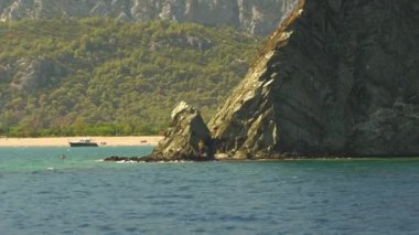 Yalnız bir balıkçı kıyıdaki kayalıklarda durur. Etrafı yüksek dağlarla çevrili, denizden izlenen bir çizgi çizer..