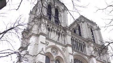 Paris 'teki Notre Dame Katedrali' nin ikonik cephesi, narin kış dalları tarafından çerçevelenmiş, gotik mimari ve cazibeyi gözler önüne seriyor..