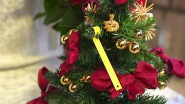 Kırmızı fiyonklarla süslenmiş küçük bir yapay Noel ağacının yakın çekimi, altın süsler ve şenlikli dekorasyon için saman süsleri.. 