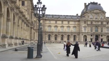 Paris, Fransa 12.20.2024 Ziyaretçiler, tarihi mimari ve simgelerle çevrili Louvre Müzesi 'nin geniş avlusunu geziyor ve keşfediyorlar.. 