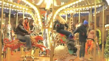 Paris, Fransa 'da 12.20.2024 Paris' teki şenlikli bir atlıkarınca ailelerin yağmurlu akşamın keyfini çıkarırken ıslak kaldırıma yansıyan parlak ışıklarla sevinçle dönüyor..