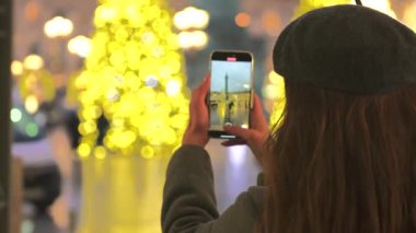 Paris, Vendome Meydanı 'nda bir kadın parıldayan Noel ışıklarını yakalıyor. Etrafı şenlikli süslemeler ve zarif bir bayram cazibesiyle çevrili..