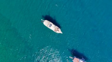 Göz kamaştırıcı bir drone, turistlerin yüzdüğü berrak denizde demirlemiş beyaz turist yatlarını tam panoramik bir perspektifle yakalıyor..