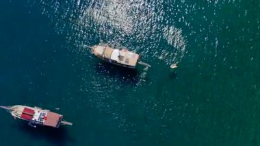 Türkiye 'nin dramatik kayalık dağları ve turkuaz sularıyla çevrili açık denizde yelken açan yatların nefes kesici insansız hava aracı görüntüsü. 