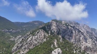 Bir dron, puslu bulutlarla çevrili kayalık tepelerin çarpıcı bir hava görüntüsünü yakalar ve dramatik ve dingin bir yüksek irtifa perspektifi sunar. 1