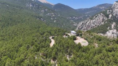 Türkiye 'de sık orman ve engebeli dağların üzerinde süzülen bir İHA, çarpıcı manzarada süzülen bir teleferiğin panoramik manzarasını sunuyor. 