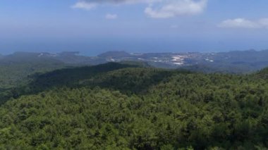 Dağlardaki sık bir ormanın üzerinde uçan bir dron, engin ve sakin bir gökyüzünün altındaki uzak denizi ve bulutları nefes kesici bir şekilde gözler önüne seriyor..