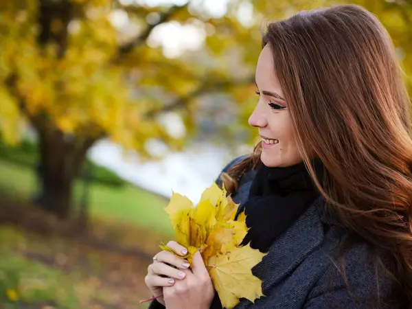 Gri ceketli sarı yaprakların yanında sonbahar resmi. Riga, Letonya. Yüksek kalite fotoğraf