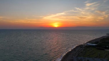 Gün batımında sakin bir kumsal manzarası dalgalanan deniz dalgaları ve huzurlu bir atmosferle sıcak altın ışıkla yıkanmış..