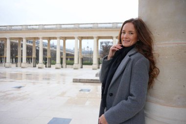 Neşeli bir kadın, Palais Royal, Paris 'in pitoresk avlusunda klasik sütunlarla çevrili bir sütuna yaslanıyor ve tarihi zarafeti kucaklıyor.. 