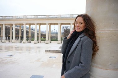 Zarif bir kadın, Palais Royal, Paris 'in avlusunda sütunlara yaslanıyor. Etrafı zamansız sütunlarla çevrili ve tarihi şehrin huzurlu atmosferinin tadını çıkarıyor.. 