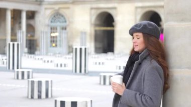 Neşeli bir Parisli kadın, hareket ve iyi titreşimlerle selfie çekerken elinde bir telefon ve kahve fincanı tutuyor.. 