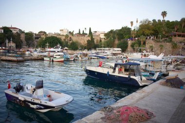 Gün batımında yemyeşil yeşil, taş duvarlar ve deniz kıyısındaki binalarla çevrili tarihi bir limanda teknelerle dolu pitoresk bir marina. Antalya yaz zamanı, Türkiye