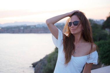 Türkiye 'nin Antalya kentinde güneş gözlüğü takan ve kıyı günbatımının tadını çıkaran şık genç bir kadın kendinden emin görünüyor..