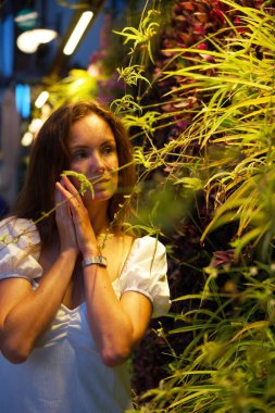 Düşünceli bir kadın, yemyeşil bitkiler ve çiçeklerle çevrili, sakin ve sakin bir atmosfer yaratan, sakin bir gece geçiriyor..