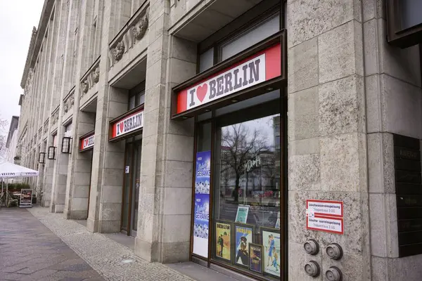 Berlin, Almanya 02.13.2025 Berlin 'deki I Love Berlin hediyelik eşya dükkanının dış cephesinde taş mimarisi, posterler ve camlarda ağaçların yansımaları yer alıyor..