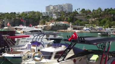 Türkiye, Antalya 10 Ekim 2024 Akdeniz yat limanına yanaştı, yemyeşil tepeler ve parlak, güneşli gökyüzü altındaki büyüleyici binalarla çevrili.