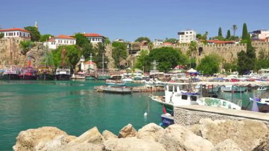 Türkiye, Antalya 10 Ekim 2024 Akdeniz 'in yemyeşil suları ve pırıl pırıl mavi sularıyla çevrili canlı bir marina, tekneler, yatlar ve tarihi taş duvarlar.. 