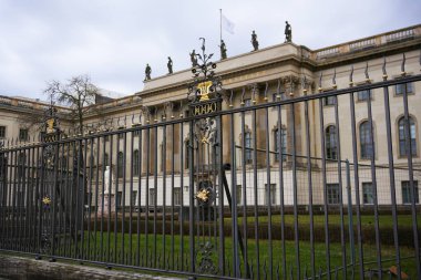 Berlin, Almanya 'daki Humboldt Üniversitesi önünde süslü siyah ve altın bir demir kapı. Karmaşık detaylar ve neoklasik mimari sergileniyor.