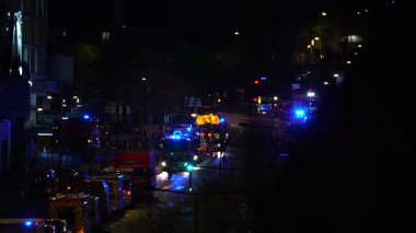 İtfaiye araçları ve ambulanslar da dahil olmak üzere birçok acil durum aracı, gece bir caddede yanıp sönen ışıklar, bir olaya müdahale ediyorlar..