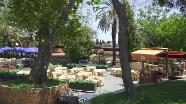 Türkiye, Antalya 10 Ekim 2024, gölgeli koltuklar, market tezgahları, açık hava restoranları ve güneşli bir gökyüzü altında yemyeşil bir yer.. 