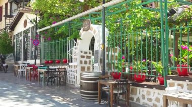 Türkiye, Antalya 10 Ekim 2024 Renkli sandalyeler, saksı bitkileri ve kırsal bir fıçı masa içeren rahat bir açık hava kafesi Avrupa tarzı bir sokakta geçiyor..