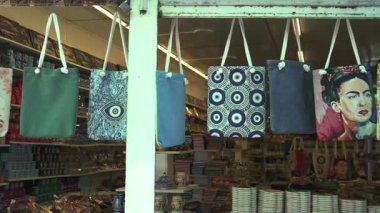 Türkiye, Antalya 10 Ekim 2024 hediyelik eşya dükkanının önünde canlı bir çanta sergisi. İçinde şeytani göz sembolleri, sanatsal kedi resimleri ve içinde geleneksel hediyeler bulunan katı renkler var.