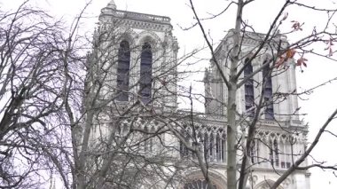 Paris 'teki Notre Dame Katedrali' nin yenilenmiş cephesi, çıplak kış ağaçları tarafından çerçevelenmiş, ikonik gotik mimarisini vurguluyor.. 