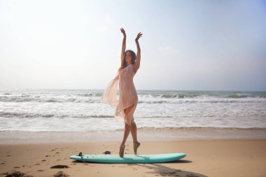 Gökyüzü ve denizin arasında duruyor, pembe elbisesi rüzgarla hareket ediyor. Balenin okyanusun sessiz gücüyle buluştuğu yumuşak, özgür bir an.. 
