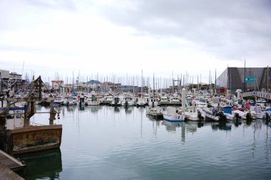 Boulogne. Fransa 03.28.2025 Paslı balıkçı teknesi modern sahil binaları yakınlarındaki küçük tekne ve yelkenlilerle dolu sessiz bir limana yanaştı..
