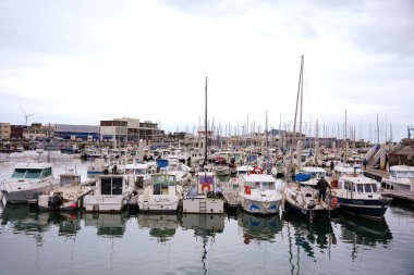Boulogne. Fransa 03.28.2025. Arka planda sakin sular ve modern binalarla huzurlu bir marinaya yanaşan sayısız küçük tekne ve yat.. 