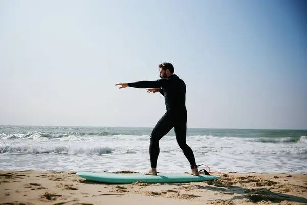 Dalgıç kıyafetli adam sörf tahtasında uzanmış güneşli gökyüzünün altında okyanus dalgalarıyla sörf pozisyonu eğitimi alıyor..