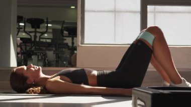 Parlak fitness alanında glute köprüsü egzersizi sırasında yan açıdan gösterilen direnç bandıyla düşük vücut kuvveti eğitimi..