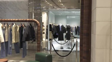 Paris, Fransa 02.20.2025 Modern butik iç mimarisi şık kotlar, ceketler ve örgü elbiseler şık tasarımlı sergi rafları ve rafları üzerinde düzgünce düzenlenmiş..