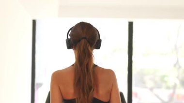 Odaklanmış koşu bandı seansı arkadan çekildi, kulaklık takan kadın iyi aydınlatılmış bir spor salonunda kardiyo ile tutarlı kalıyor..