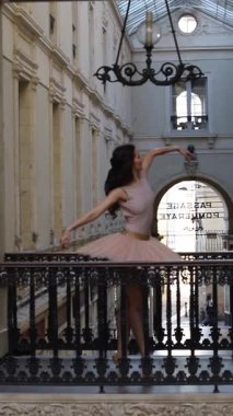 Yumuşak pembe etekli balerin, zarif bir şekilde şık mimarisi ve kemerleriyle klasik bir alışveriş galerisinde poz veriyor.. 