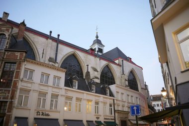Bruxelles, Belçika 04.01.2025 Büyülü bir Gotik kilisenin kemerli camları büyüleyici dükkanların ve Brüksel 'in merkezindeki dar sokakların üzerinde alacakaranlıkta yükseliyor.. 