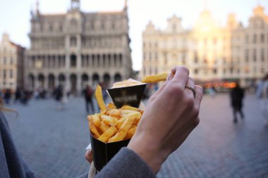 Brüksel 'in Grand Place şehrinde soslu klasik Belçika patateslerinin arka plandaki tarihi binalara altın ışıkla yakın plan çekimleri..