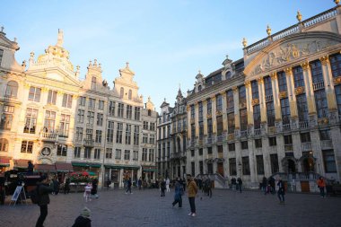 Bruxelles, Belçika 04.01.2025 Ziyaretçiler, altın akşam güneşi ışığıyla aydınlatılmış tarihi binalarla çevrili ikonik Grand Place 'in tadını çıkarıyorlar.. 