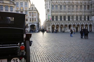 Bruxelles, Belçika 04.01.2025 Klasik bir araba, tarihi binalar ve sembolik meydanın keyfini çıkaran turistlerin yer aldığı Grand Place manzarası. 