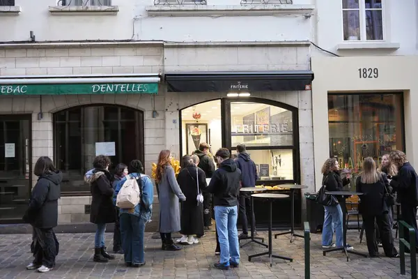 Bruxelles, Belçika 04.01.2025 Bir grup insan Belçika 'da kalabalık bir friteride sıra bekliyor, sokak yemeklerinin tadını çıkarıyor ve sokak ortasında sosyalleşiyorlar.. 