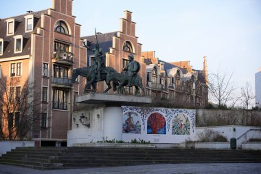 Bruxelles, Belçika 04.01.2025 Bronz binicilik heykeli, Brüksel 'in modern bir semtinde, canlı sanat seramikleri olan duvar resmi yakınındaki bir kaidede duruyor.. 