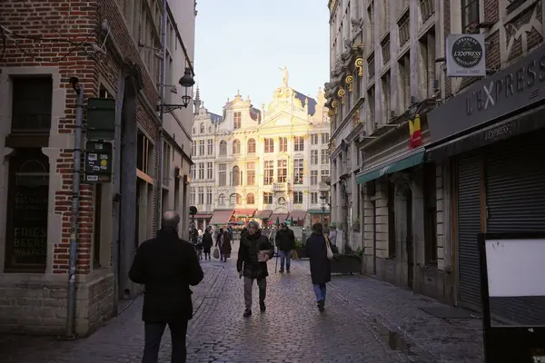 Bruxelles, Belçika 04.01.2025 Brüksel 'de, tarihi binalar ve dükkanlarla çevrili güneşli Grand Place' e doğru yürüyen insanlarla dolu bir cadde..